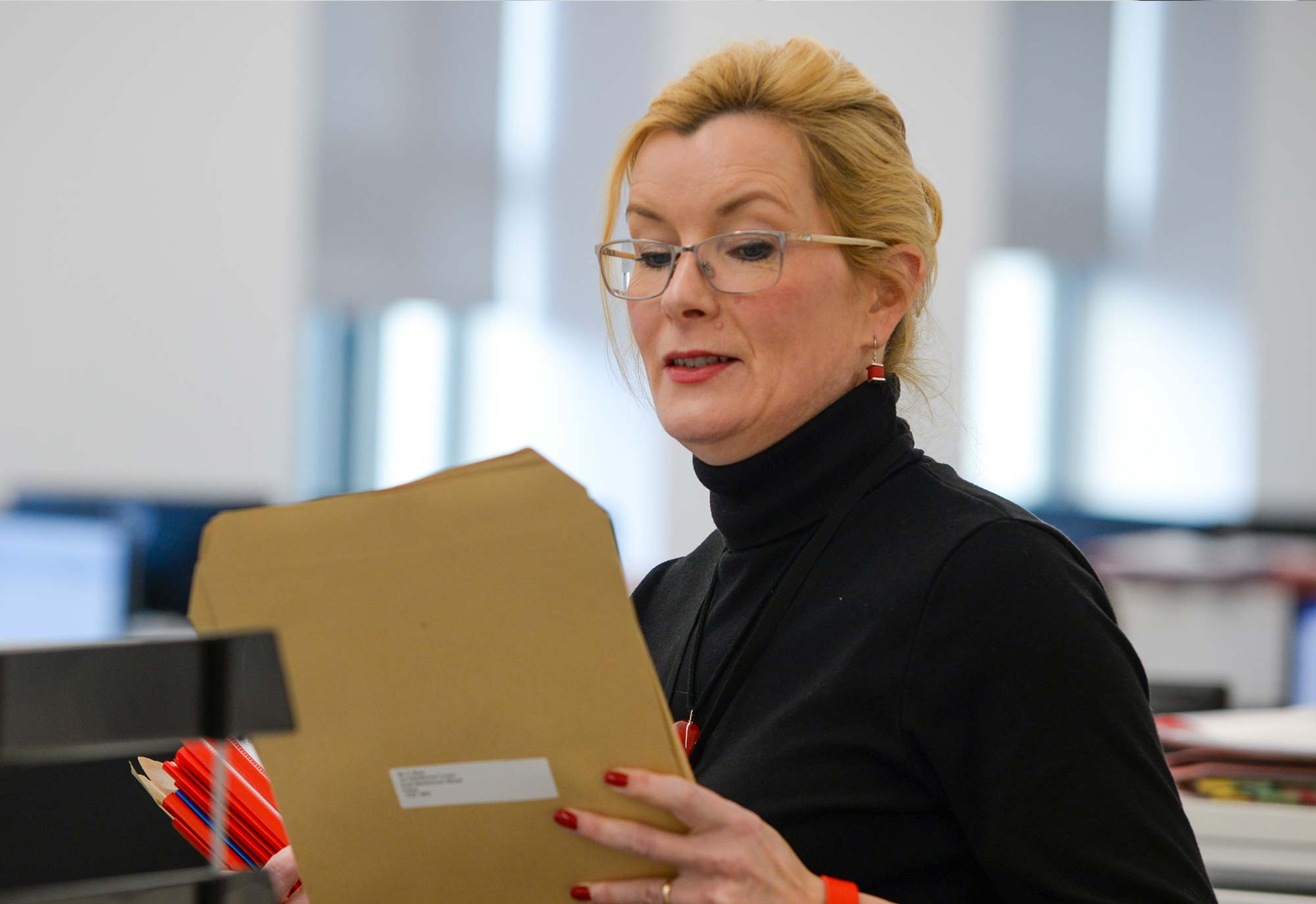 man stands at filing cabinet reading documentation